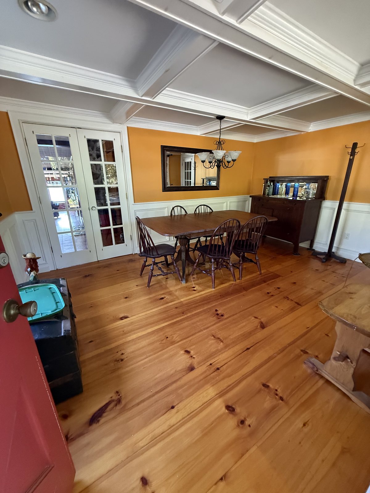Dining room with a coffered ceiling, white wainscoting and a pine plank floor, dusted and floors cleaned after a house cleaning visit