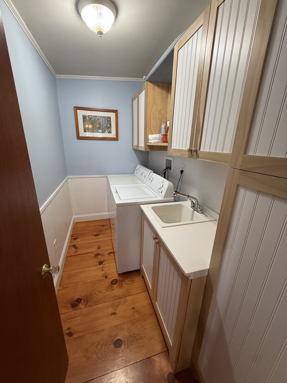 Small laundry room with a washer, a utility sink and beadboard cabinets, wiped down and floor cleaned after a house cleaning visit