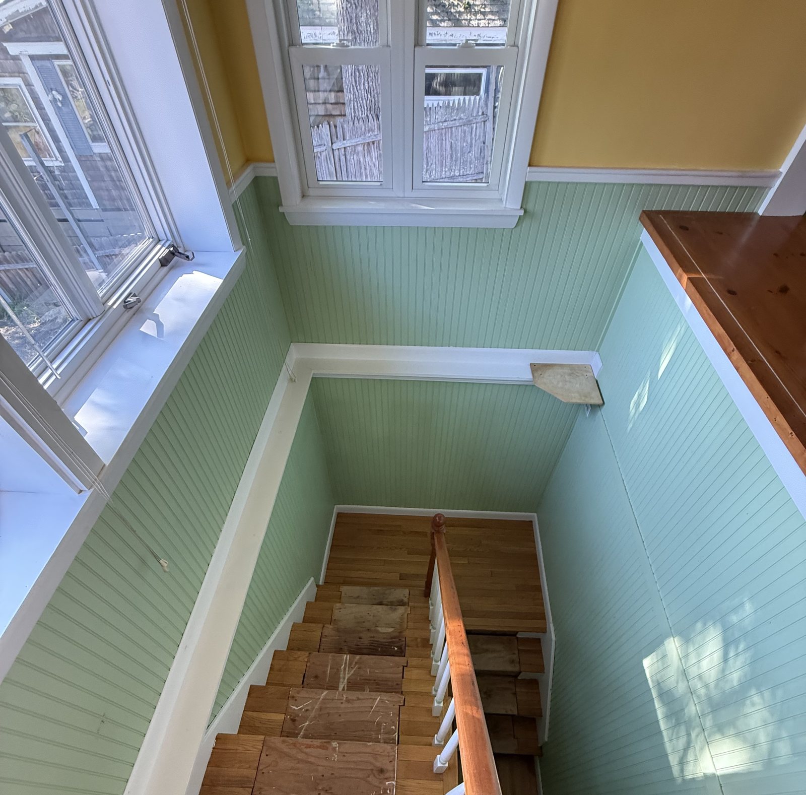 Stairwell with green beadboard walls, white trim and wooden treads, dusted and vacuumed after a house cleaning visit