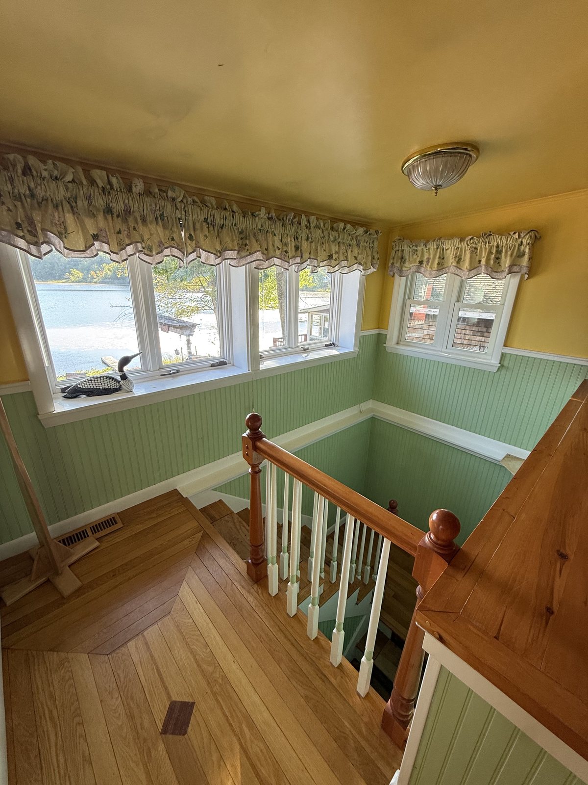 Upstairs landing with green beadboard, a window wall looking out over the lake and a polished wood floor after a house cleaning visit